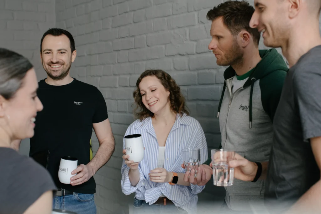 Eine Gruppe von fünf Personen steht in einer lockeren Runde zusammen und unterhält sich lächelnd.