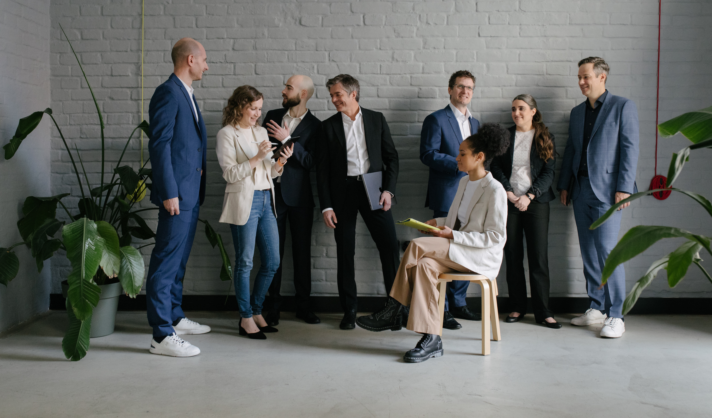 Team von Frauen und Männern im Büro, die zusammen stehen und sich unterhalten.